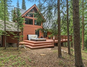 Une cabane dotée d’une terrasse, entourée d’arbres.