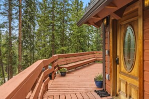 A wooden deck with a railing, potted plants, and a door with a window. - The Rendezvous Chalet – Spacious Mountain Retreat (Breckenridge)