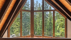 Ein Zimmer mit einem großen Fenster und Blick auf einen Wald.