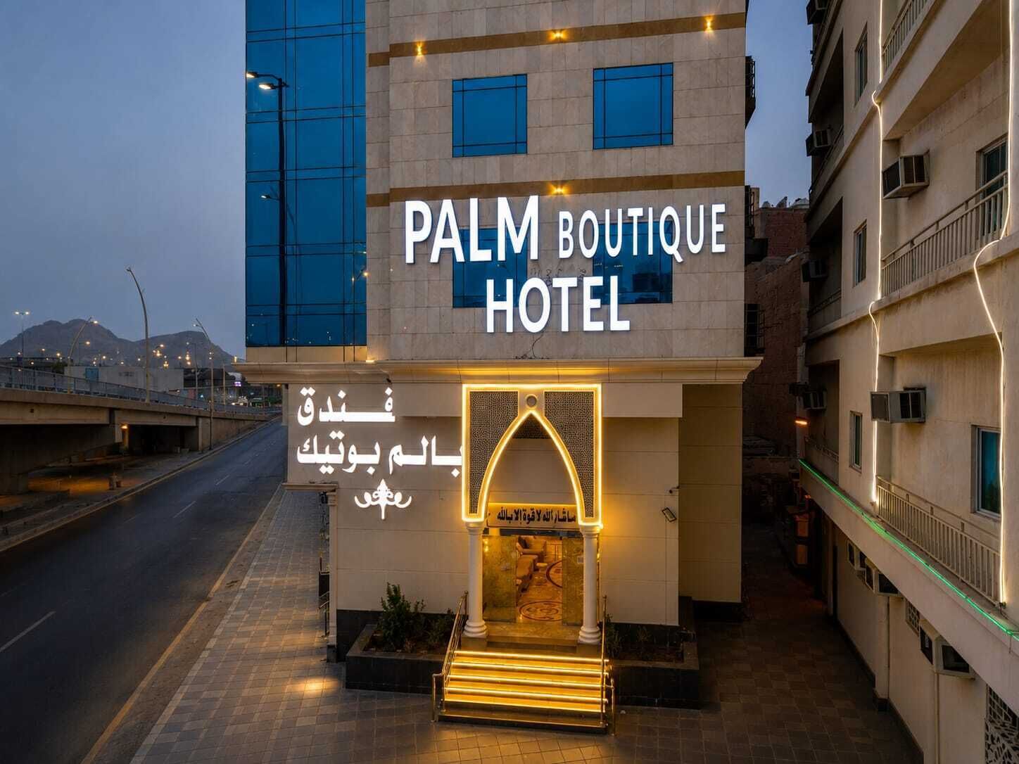 The exterior of the Palm Boutique Hotel with a modern facade, a prominent entrance, and a sign in multiple languages.