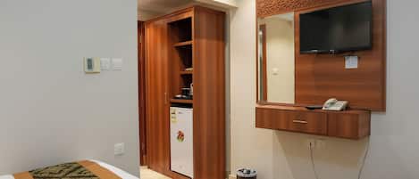 Une chambre d’hôtel équipée d’un lit, d’une armoire, d’un réfrigérateur, d’une poubelle, d’un téléviseur fixé au mur et d’un téléphone.