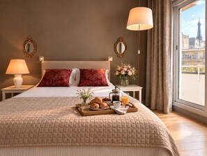 A hotel room with a large bed, two bedside lamps, a view of the Eiffel Tower, and a breakfast tray on the bed. - L'appartement Paul Doumer (Paris)