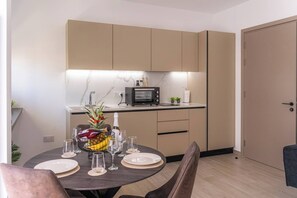 Eine moderne Küche mit Mikrowelle, kleinem Kühlschrank und Essecke, gedeckt für zwei Personen.
