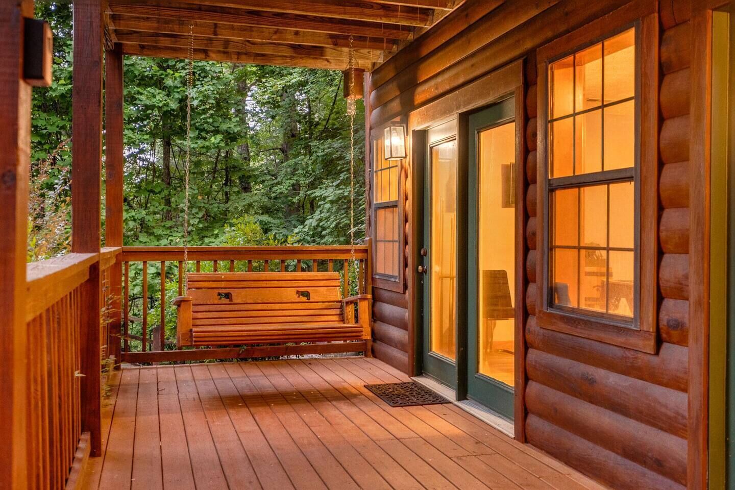 A wooden cabin with a porch, a bench, and a door with glass panels.