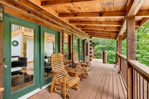 Una terraza de madera con mobiliario exterior y vistas al follaje circundante.
