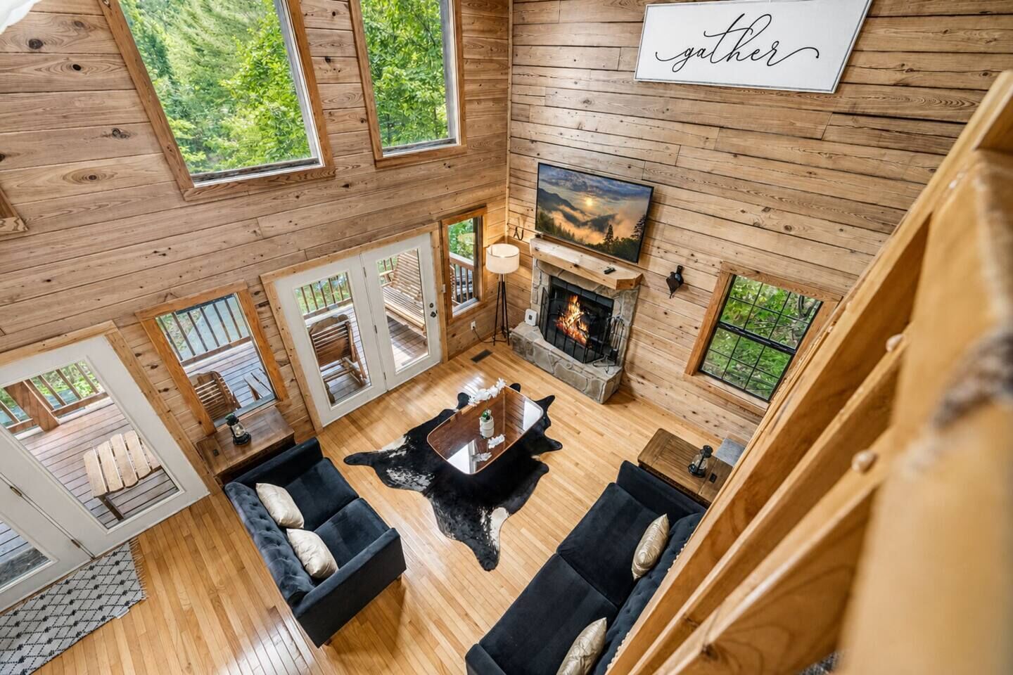 Un interior de cabaña espacioso, con chimenea, paredes de madera y ventanas amplias.