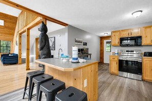 Eine moderne Küche mit Holzschränken, einem Edelstahlbackofen und einer Kaffeestation.