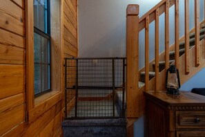 A wooden staircase with a metal gate at the top, a lantern on a table, and a window with blinds. - Nerf Gun Wall, Theater/Games, Hot Tub, Sleeps 14 (Sevierville)