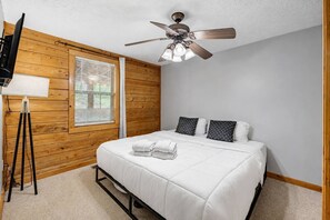 A bedroom with a bed, a ceiling fan, a window with blinds, and a tripod stand. - Nerf Gun Wall, Theater/Games, Hot Tub, Sleeps 14 (Sevierville)