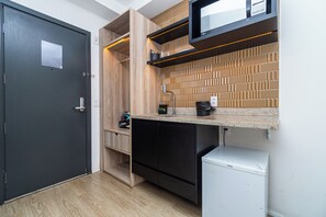 Eine kompakte Küche mit integriertem Geschirrspüler, Mikrowelle und Kaffeemaschine auf der Arbeitsplatte.