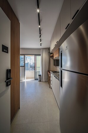A modern kitchen with stainless steel appliances, a wooden door, and a view to the outside. - Nik Sunset  (São Paulo)