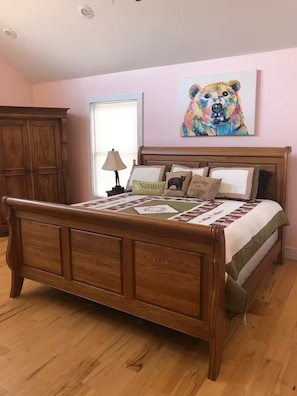 Ein Schlafzimmer mit einem hölzernen Bett, einer Steudecke und einem Bärenbild an der Wand.