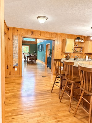 A wooden interior with a dining area, kitchen, and a hallway leading to another room. - Blackberry Heaven Lodge (Lenoir)