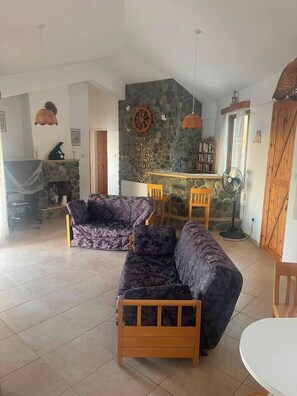 A living room with a stone fireplace, a wooden dining table, and a sofa.