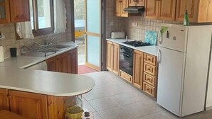 A kitchen with wooden cabinets, a white countertop, a stove, and a refrigerator. - Seaview Villa in Pomos with private Swimming pool (Pomos)