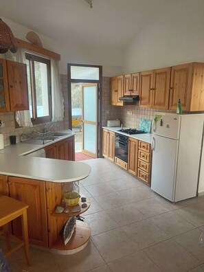 Eine Küche mit Holzschränken, einer weißen Arbeitsplatte, einem Herd und einem Kühlschrank.