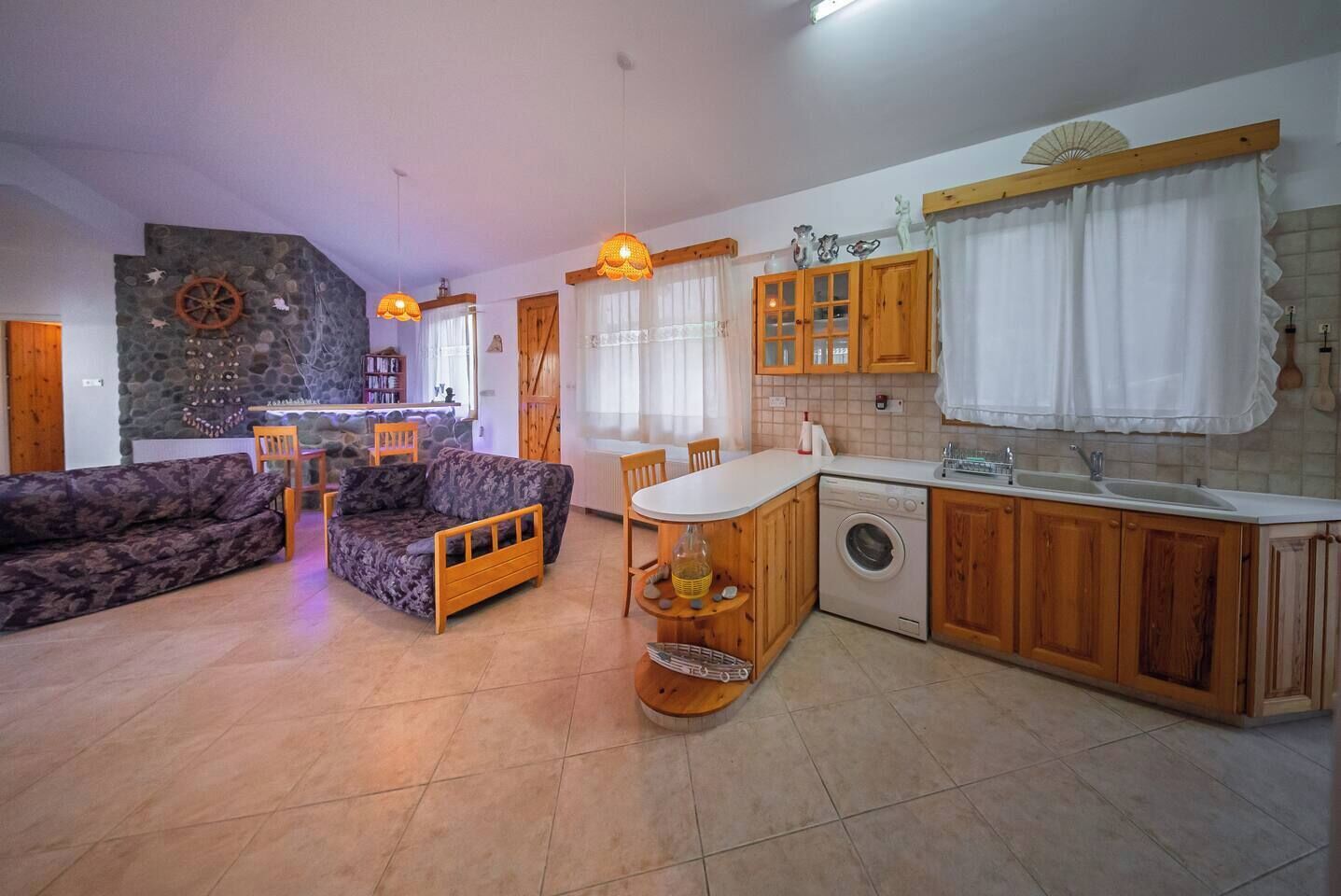 A compact living space with a sofa, dining table, and kitchen area including a washing machine.