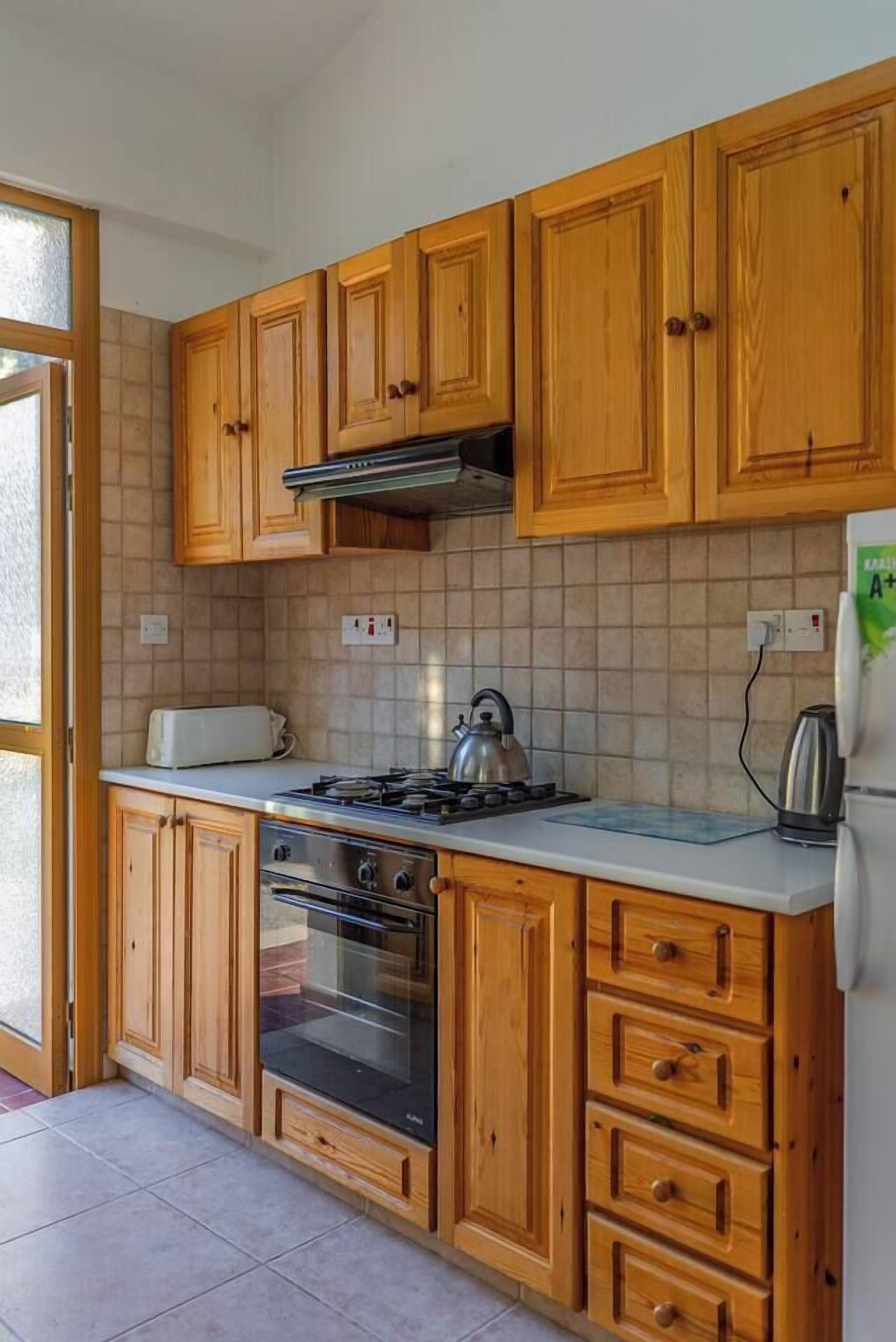 Una cocina con armarios de madera, una estufa a gas, un horno y un refrigerador.
