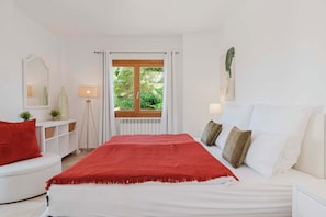 A bedroom with a bed, a window, a bedside table, and a lamp. - Villa Casa Aura for 8 people near the beach in Cala dór (Cala d'Or)