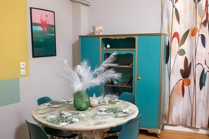 Un coin repas avec une table ronde, des chaises, un buffet et un tableau accroché au mur.