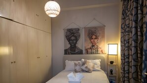 A bedroom with a bed, pillows, a bedside table, a lamp, and two wall-mounted artworks. - Relax City Apartment with Private Terrace, Wi-Fi and Air Conditioning (Aigio)