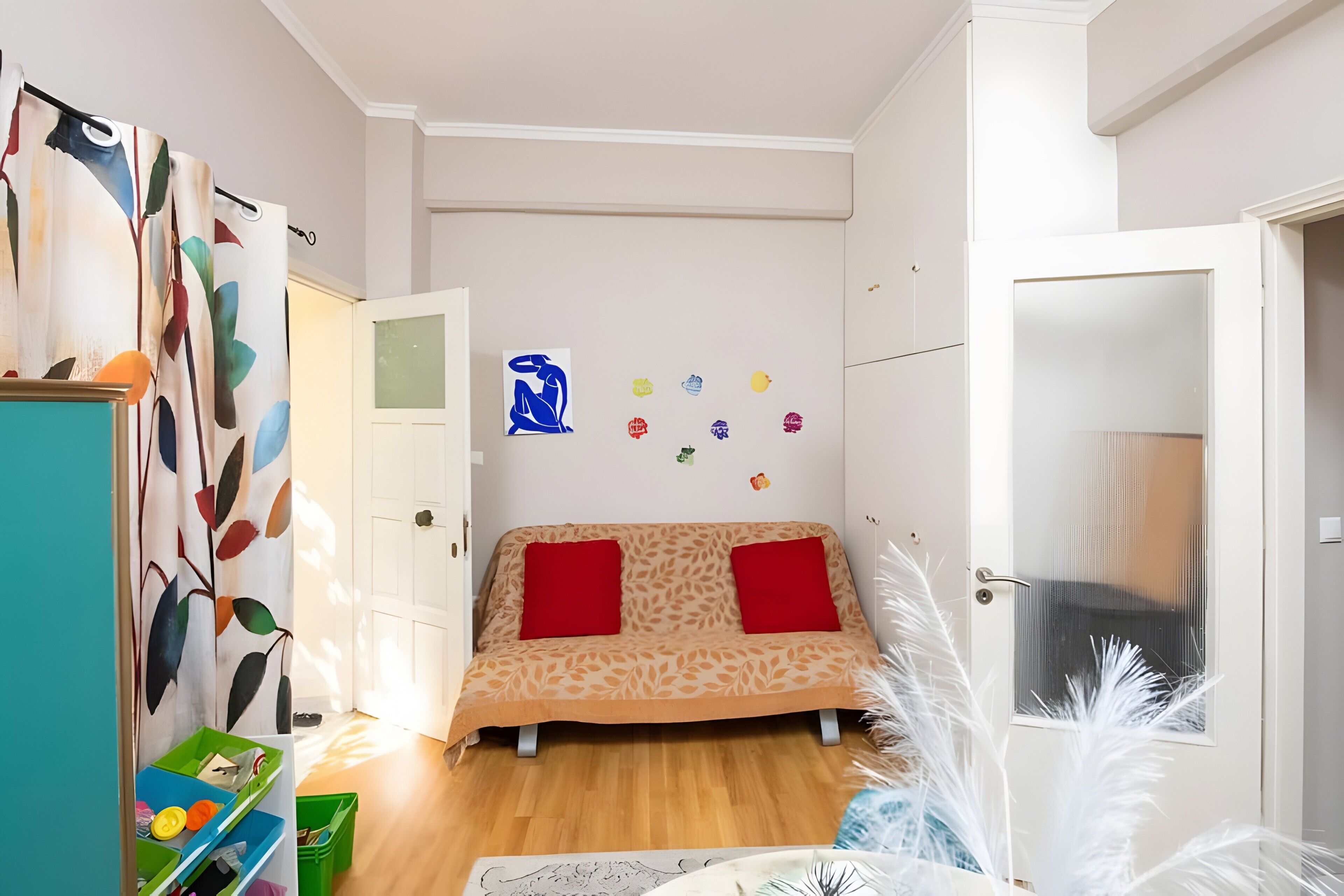 A room with a bed, a wardrobe, a green storage unit, and a door with a frosted glass panel.