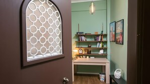 A room with a door featuring a decorative window, a desk with a lamp, and shelves with books and decorative items. - Relax City Apartment with Private Terrace, Wi-Fi and Air Conditioning (Aigio)