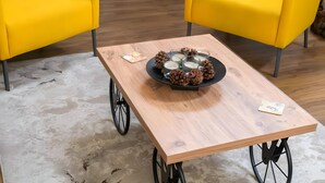 A wooden table with a black tray holding candles and pine cones, flanked by yellow chairs. - Relax City Apartment with Private Terrace, Wi-Fi and Air Conditioning (Aigio)