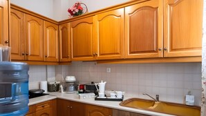 A kitchen with wooden cabinets, a sink, and various appliances. - Relax City Apartment with Private Terrace, Wi-Fi and Air Conditioning (Aigio)