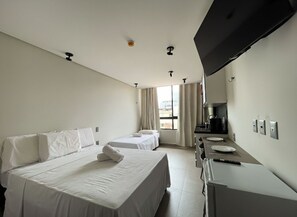 A hotel room with two beds, a desk, a flat-screen TV, and a window with curtains. - Acqua by Hosppedar (João Pessoa)