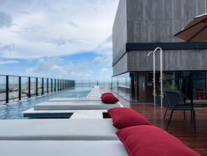 A modern outdoor pool area with lounge chairs and a view of the ocean. - Acqua by Hosppedar (João Pessoa)