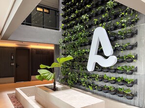 A modern interior with a large 'A' sign, a wall-mounted plant display, and a minimalist staircase. - Acqua by Hosppedar (João Pessoa)