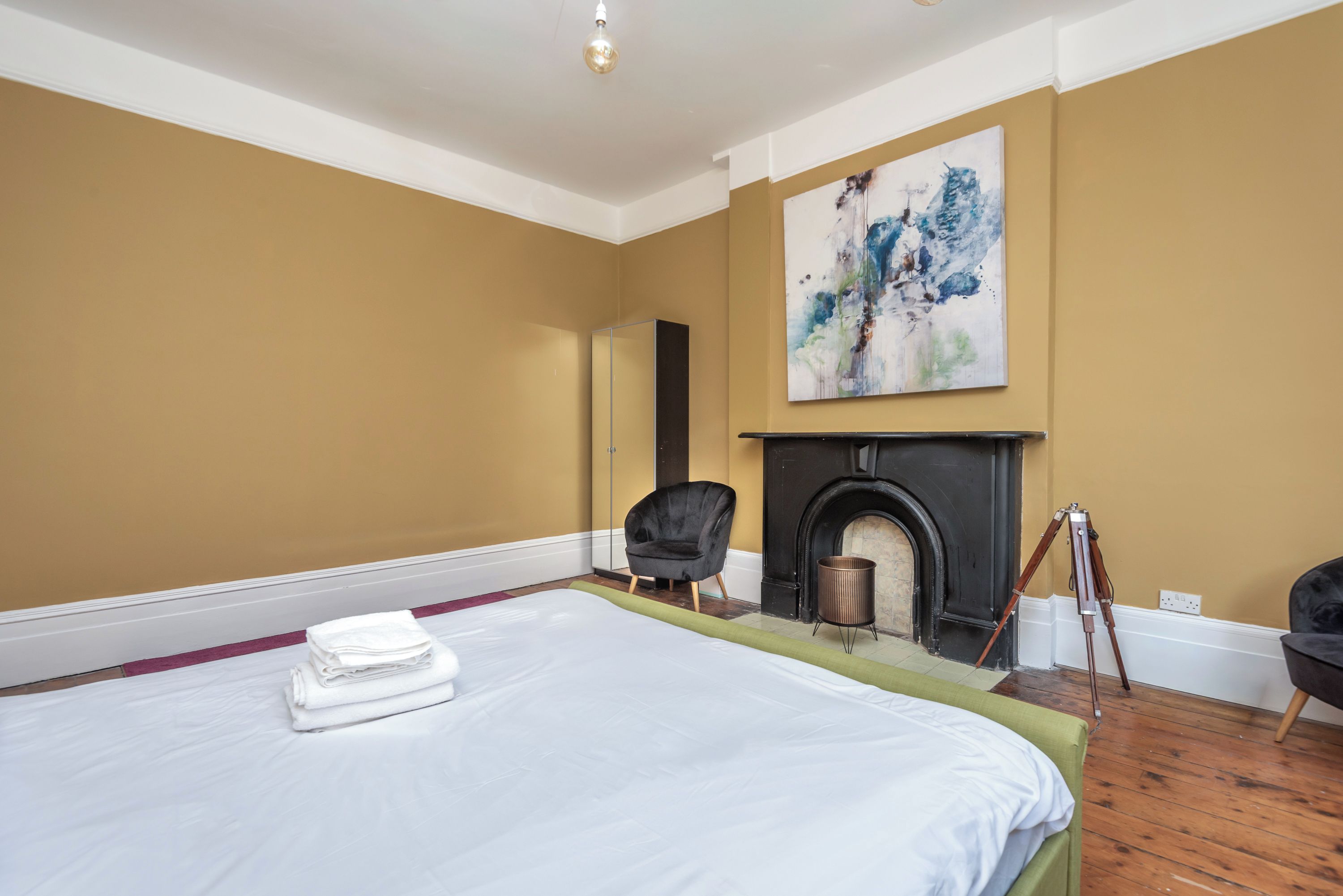 Ein Hotelzimmer mit Bett, Sessel, Kamin und einem Gemälde an der Wand.