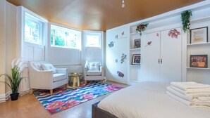 Quarto com cama, sofá, cadeira, mesa pequena, guarda-roupa e janela.