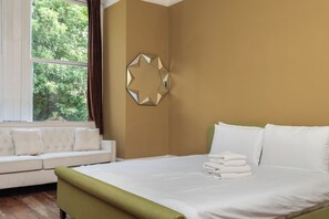A hotel room with a bed, a sofa, and a window with curtains. - Characterful 3BDR Garden Flat in Streatham Hill (Greater London)