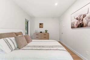 Ein Schlafzimmer mit einem Bett, einem Schminktisch, einem Wandbild und einer Tür.