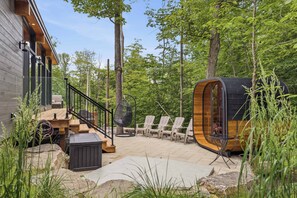 Eine Holzhütte mit einer Terrasse, Sitzgelegenheiten im Freien und einer runden Holzkonstruktion.