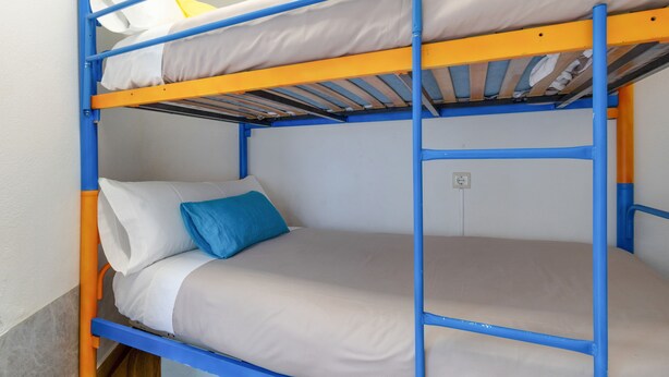 Una cama litera con dos niveles, cada uno con almohada y colchón.