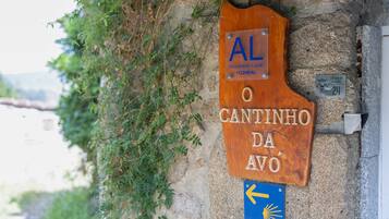 Un letrero de madera con el texto 'AL O CANTINHO DA AVO' y una señal azul direccional con una flecha.