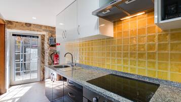 Una cocina moderna con estufa integrada, armarios de acero inoxidable y un salpicadero de azulejos amarillos.