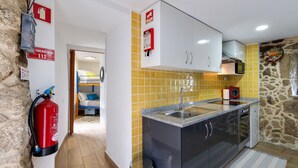 Cocina compacta con lavamanos, armarios y extintor.