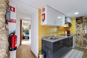 A compact kitchen with a sink, cabinets, and a fire extinguisher.