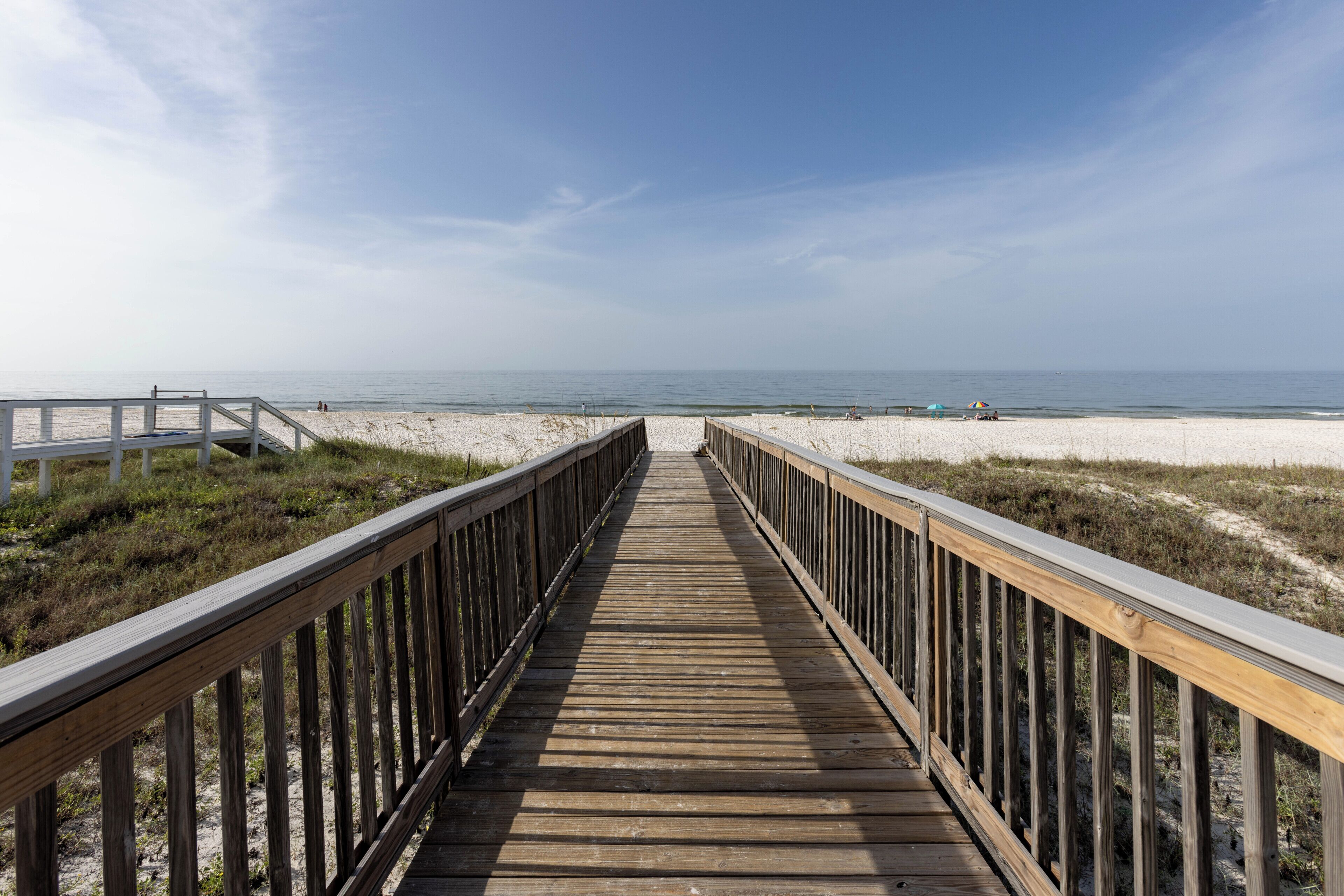 A wooden boardwalk leading to a beach with a clear sky.