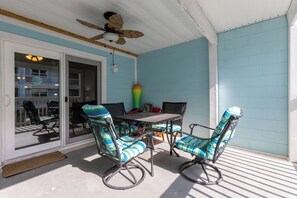A covered patio with a table and chairs, a ceiling fan, and a view through a glass door. - Lagoon Run 106 - Best of Both Worlds: Beach Access & Lagoon Dock! (Gulf Shores)