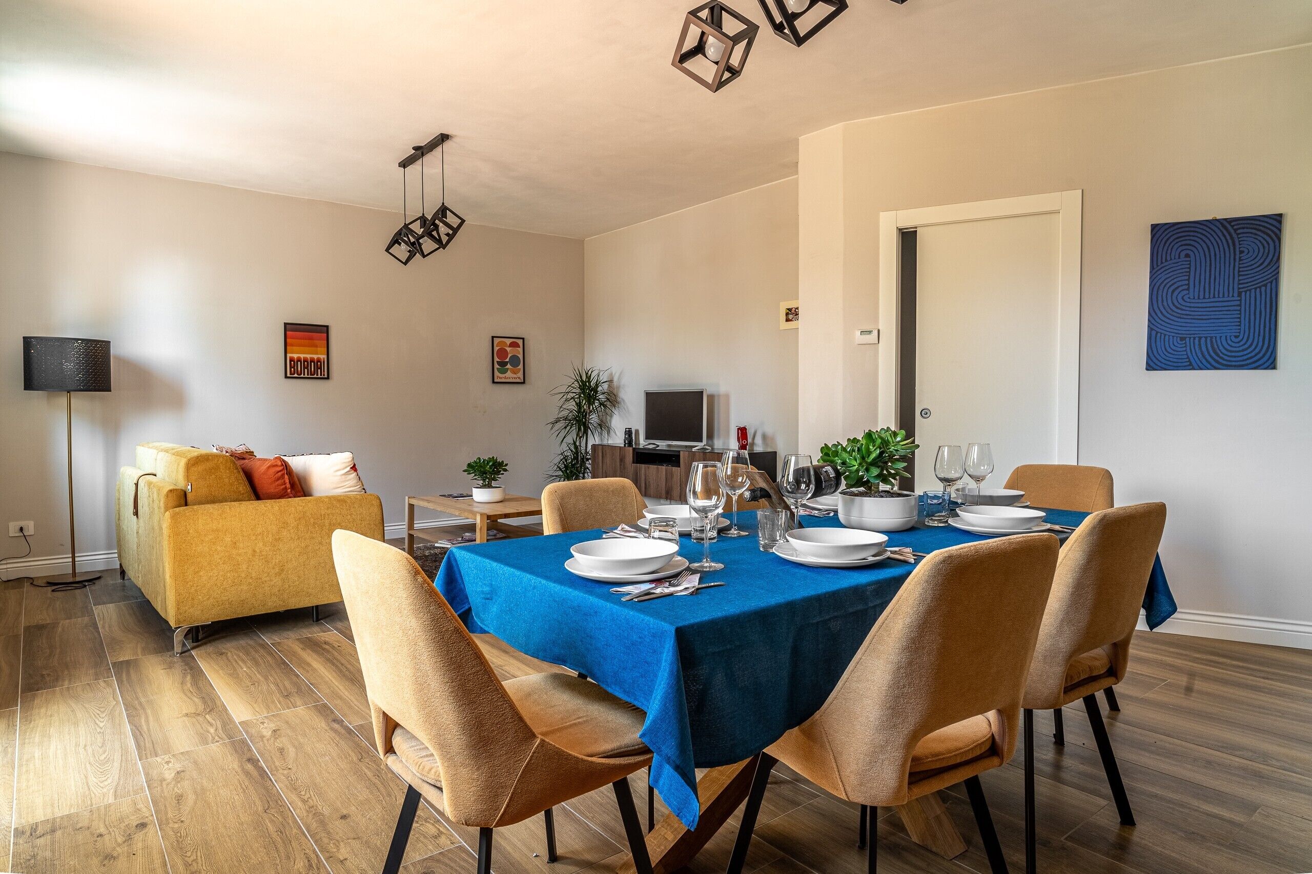 A dining area with a blue tablecloth, chairs, and a television in the background.