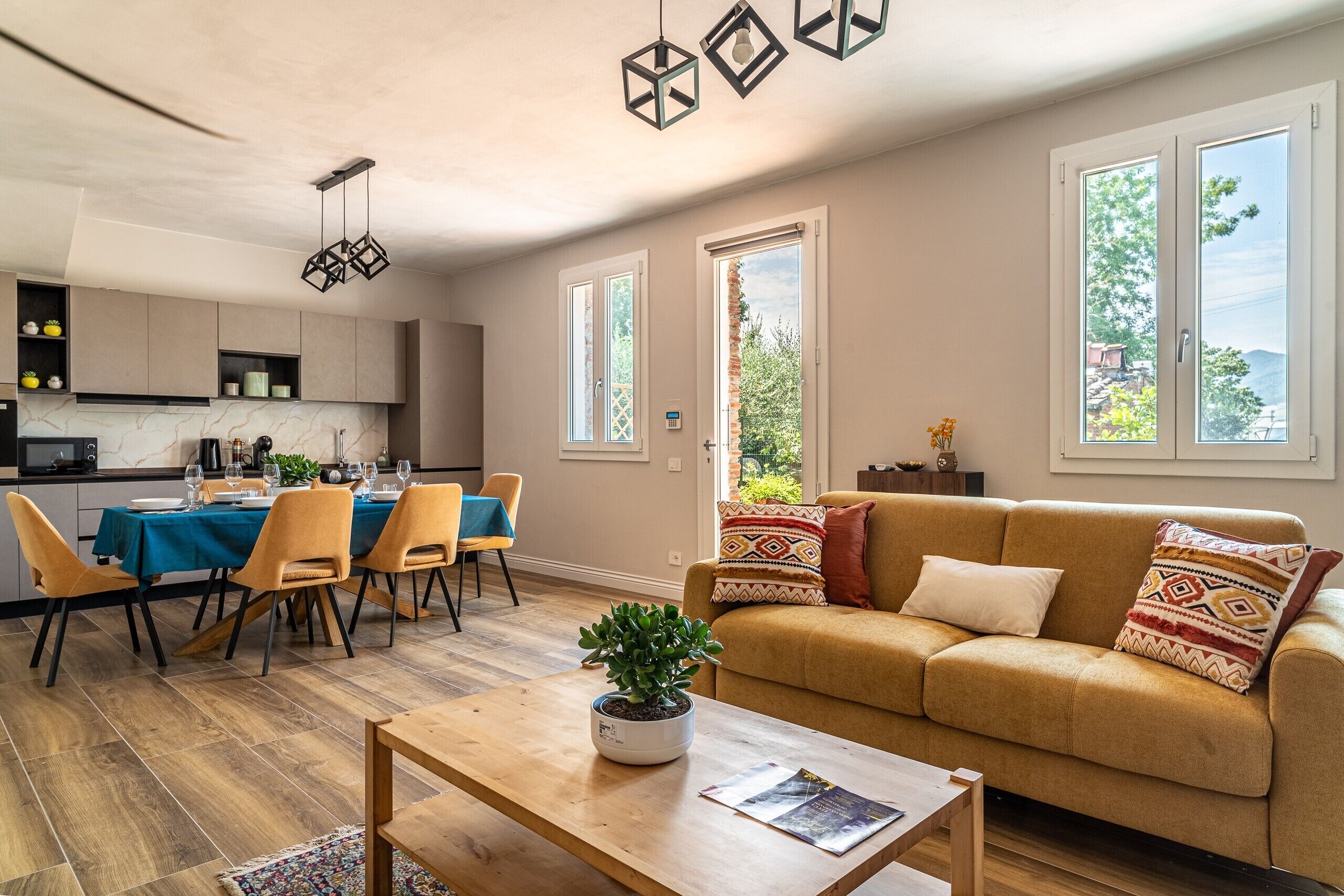 A modern living room with a sofa, coffee table, and dining area with chairs and a table set for a meal.