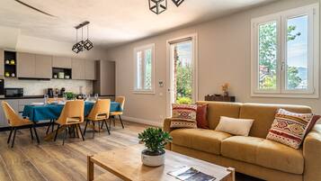 A modern living room with a sofa, coffee table, and dining area with chairs and a table set for a meal.