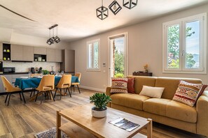 Ein modernes Wohnzimmer mit Sofa, Couchtisch und Essbereich mit Stühlen und einem Tisch, der für eine Mahlzeit gedeckt ist.