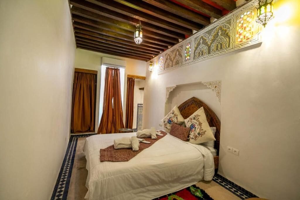 A bedroom with a bed, a telephone, and a decorative wall.