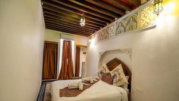 A bedroom with a bed, a telephone, and a decorative wall. - Dar Rass Jnane (Fes)